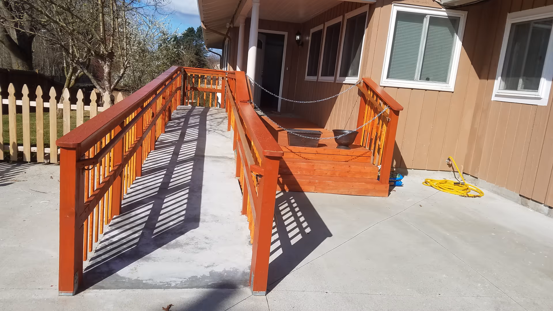 Orange wooden ramp and deck lead to a brown building entrance with a porch.