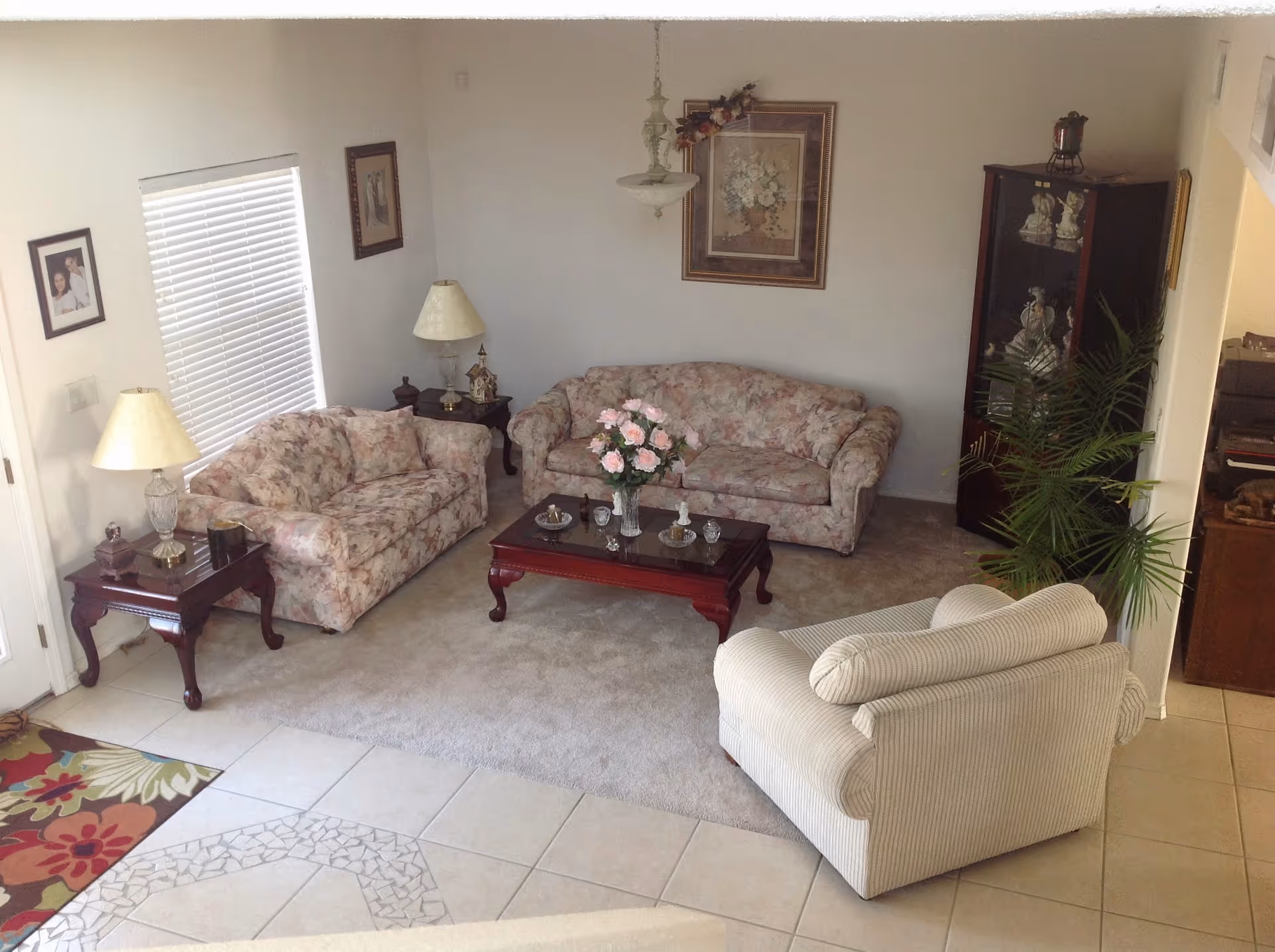 Living room at Angel's Heaven Adult Foster Home with floral sofas, coffee table, lamps, and plants.