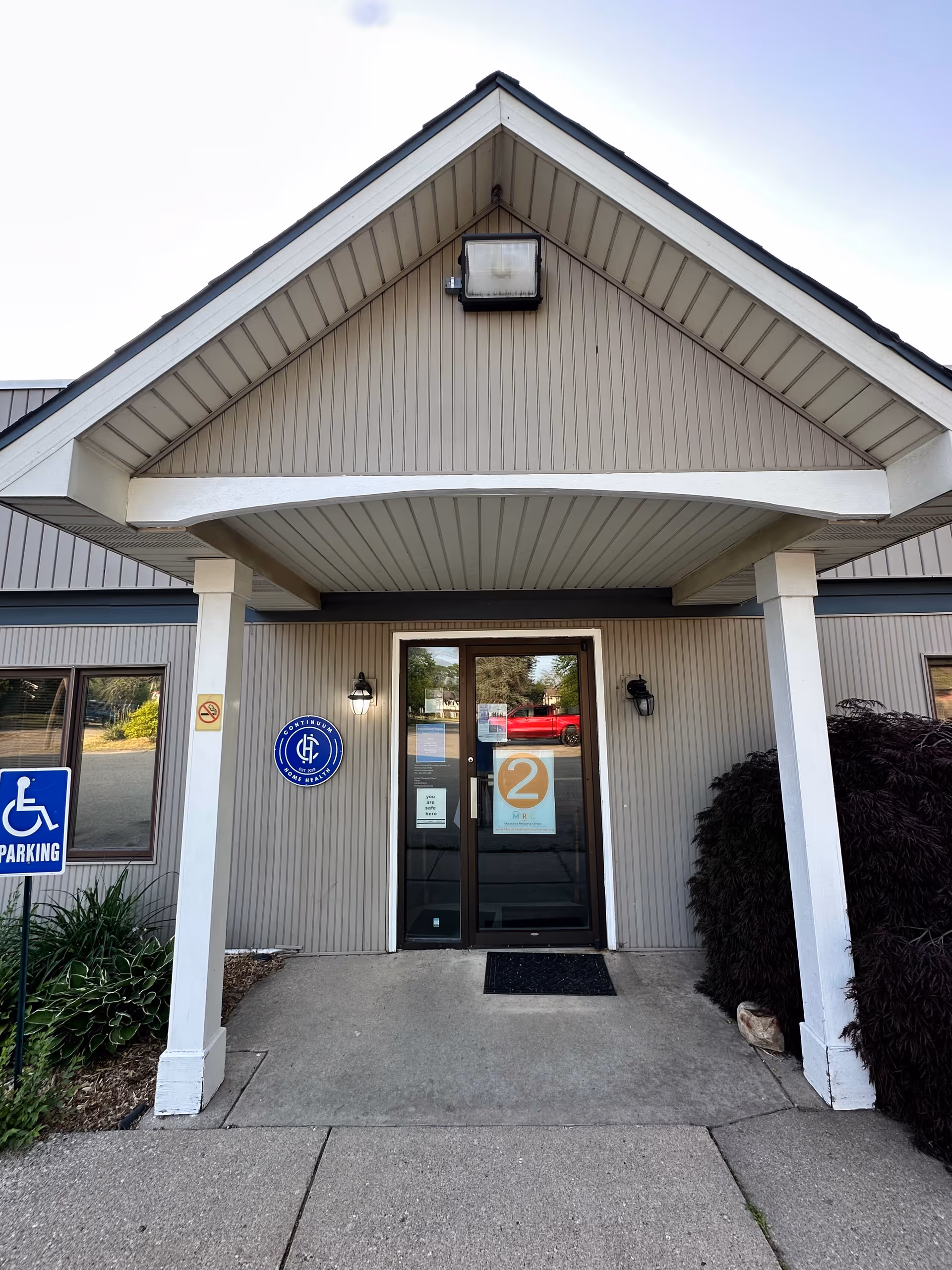 Exterior view of a building entrance with a covered porch and handicap sign.
