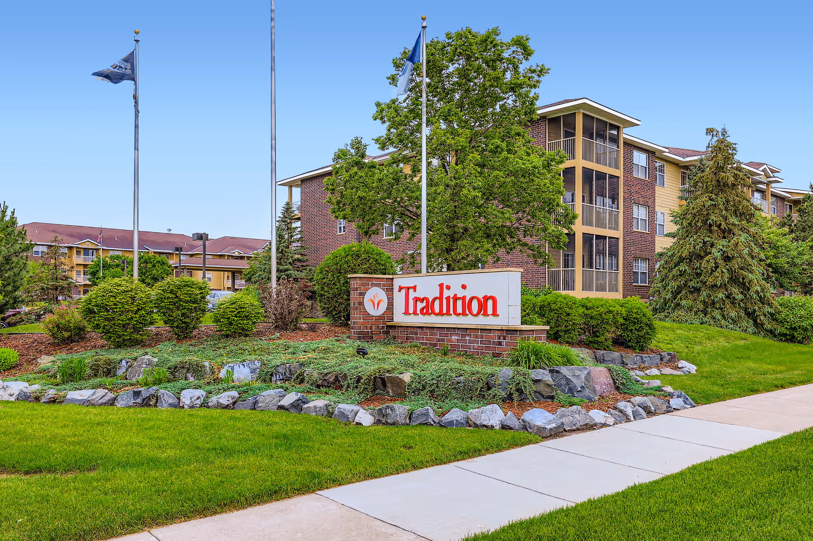 Exterior view of Tradition senior living campus with landscaped entrance and sign