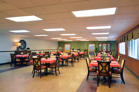 A spacious dining hall with pink tablecloths and many arranged tables indoors.