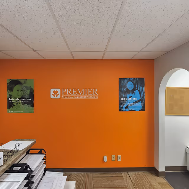 Interior lobby with orange wall, Premier Financial Management Services logo, and posters.