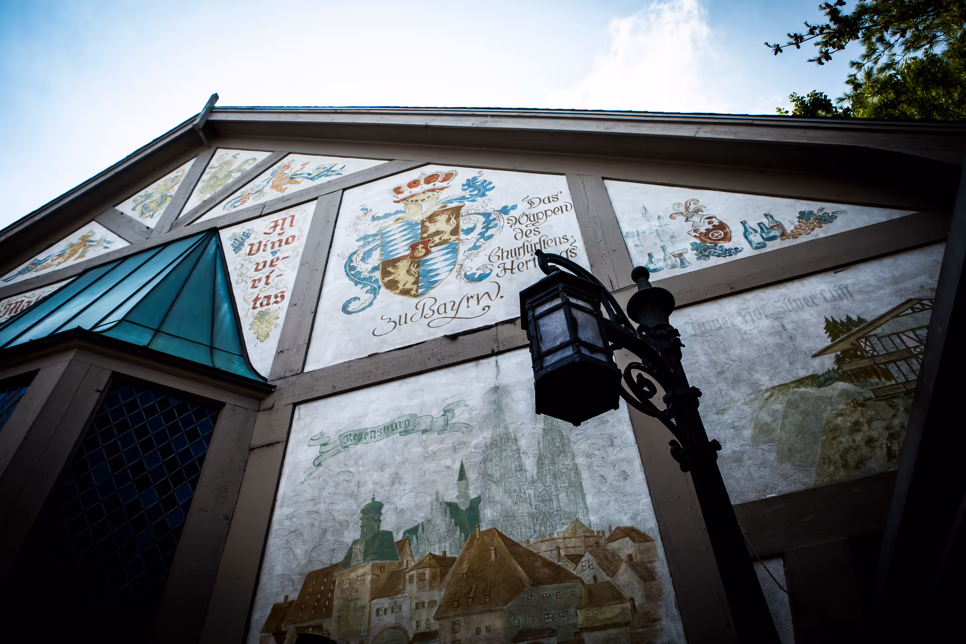 Exterior wall with murals, lantern, and teal glass awning on a building.