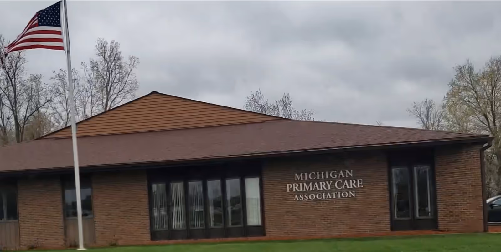 Brick building with Michigan Primary Care Association sign and American flag in front