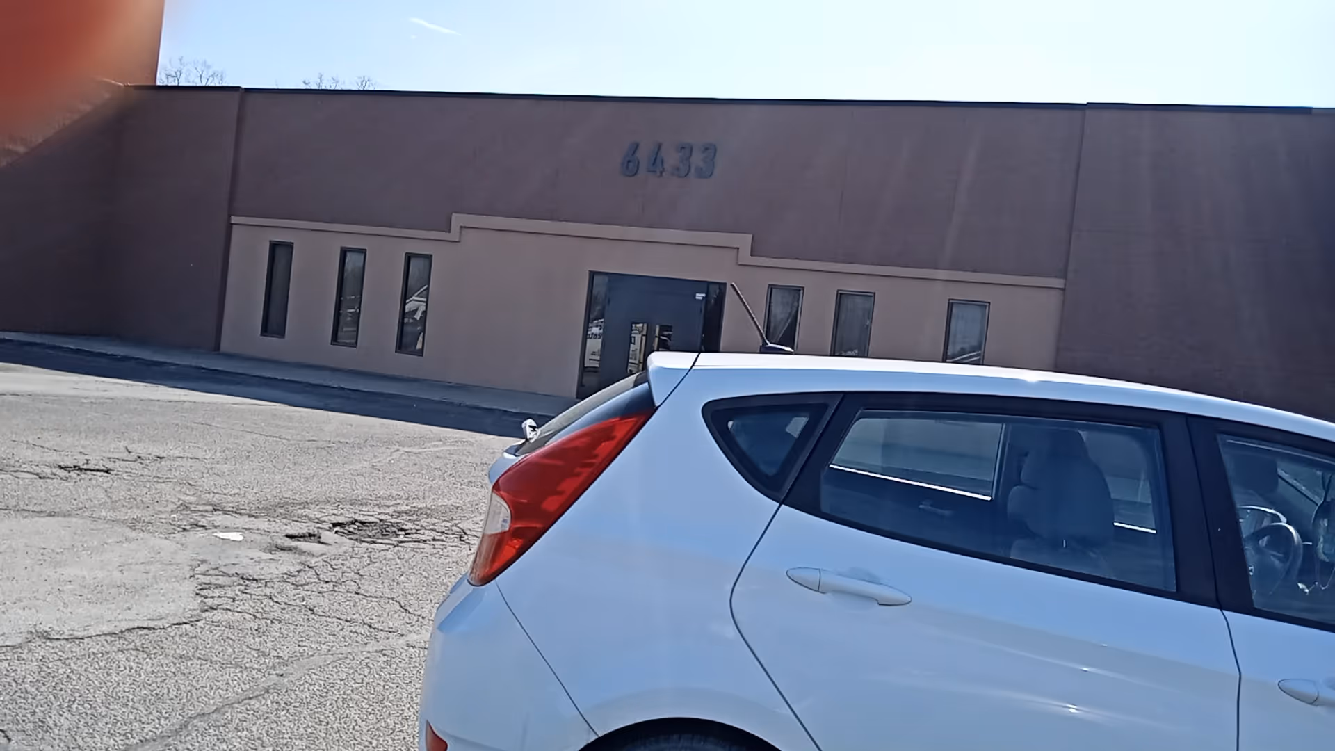 A white car parked in front of a beige senior living facility labeled 6433.