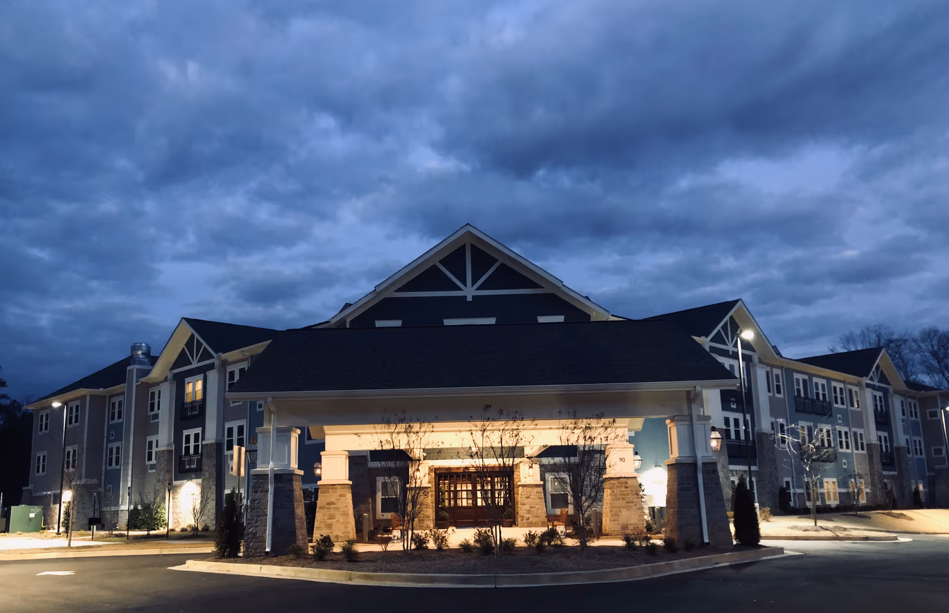 Exterior view of The Phoenix at James Creek, a multi-story senior living building with lit entrance.