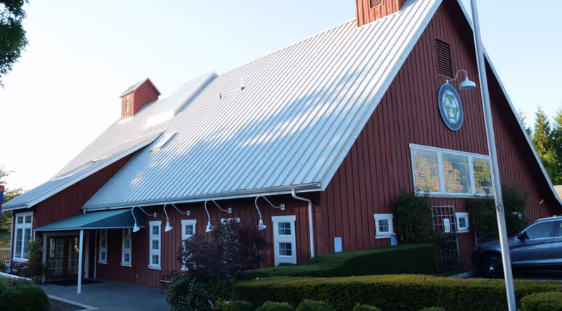 Red barn-style senior living building with metal roof and landscaped front.