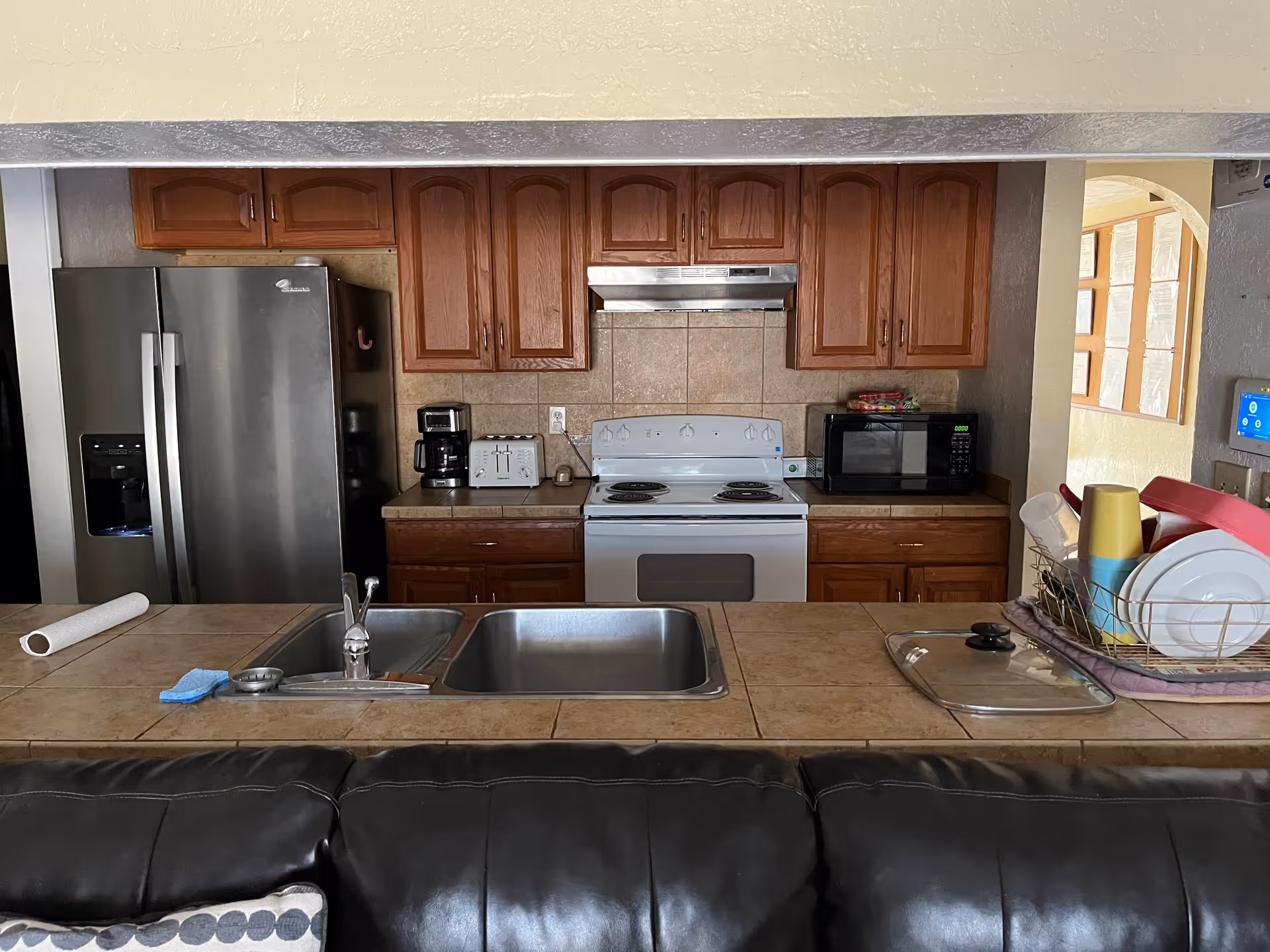 Open kitchen area with stainless refrigerator, stove, microwave, and sink.