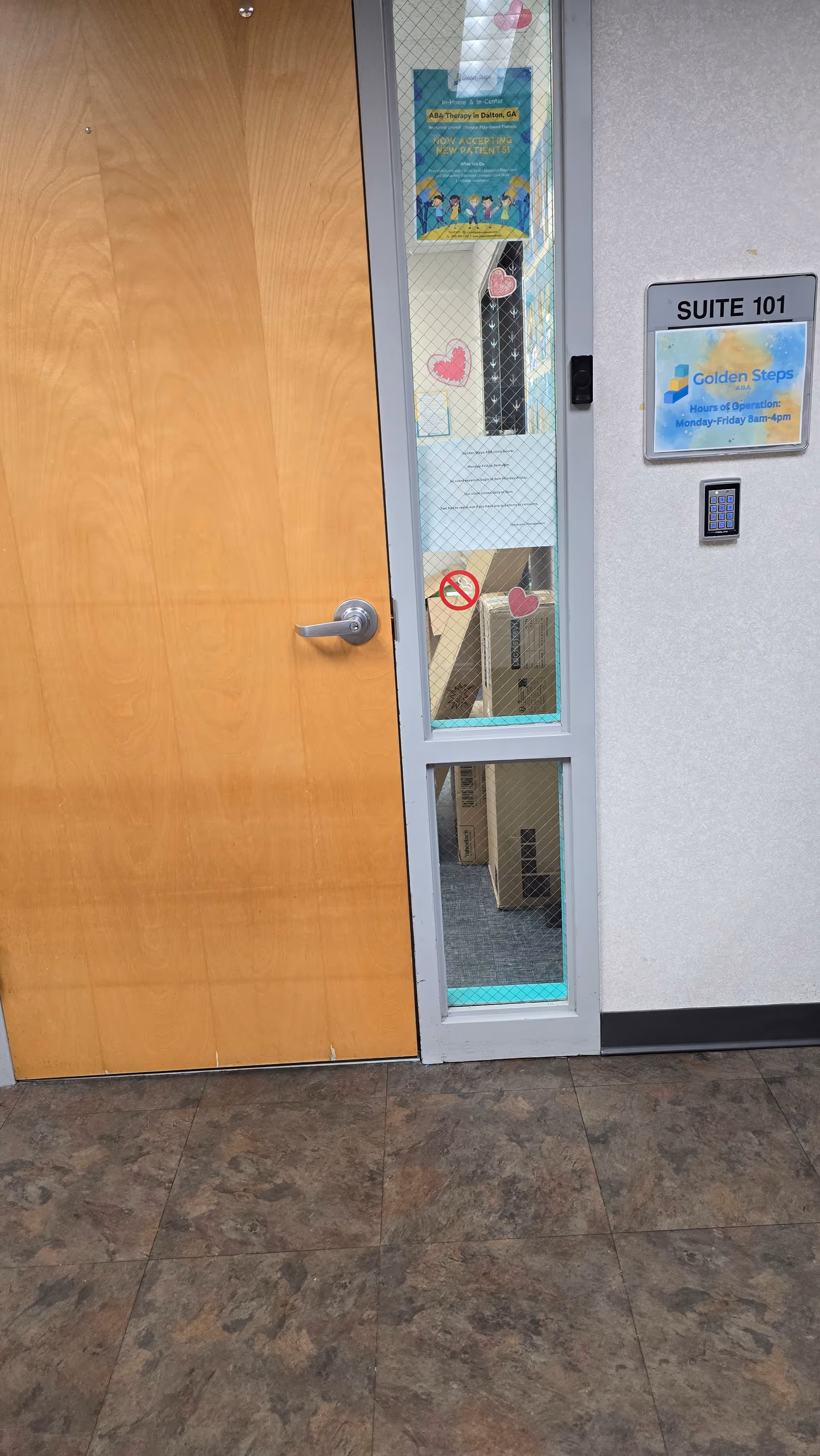 Interior hallway with a glass-paneled suite door labeled 101 and pink heart decals.