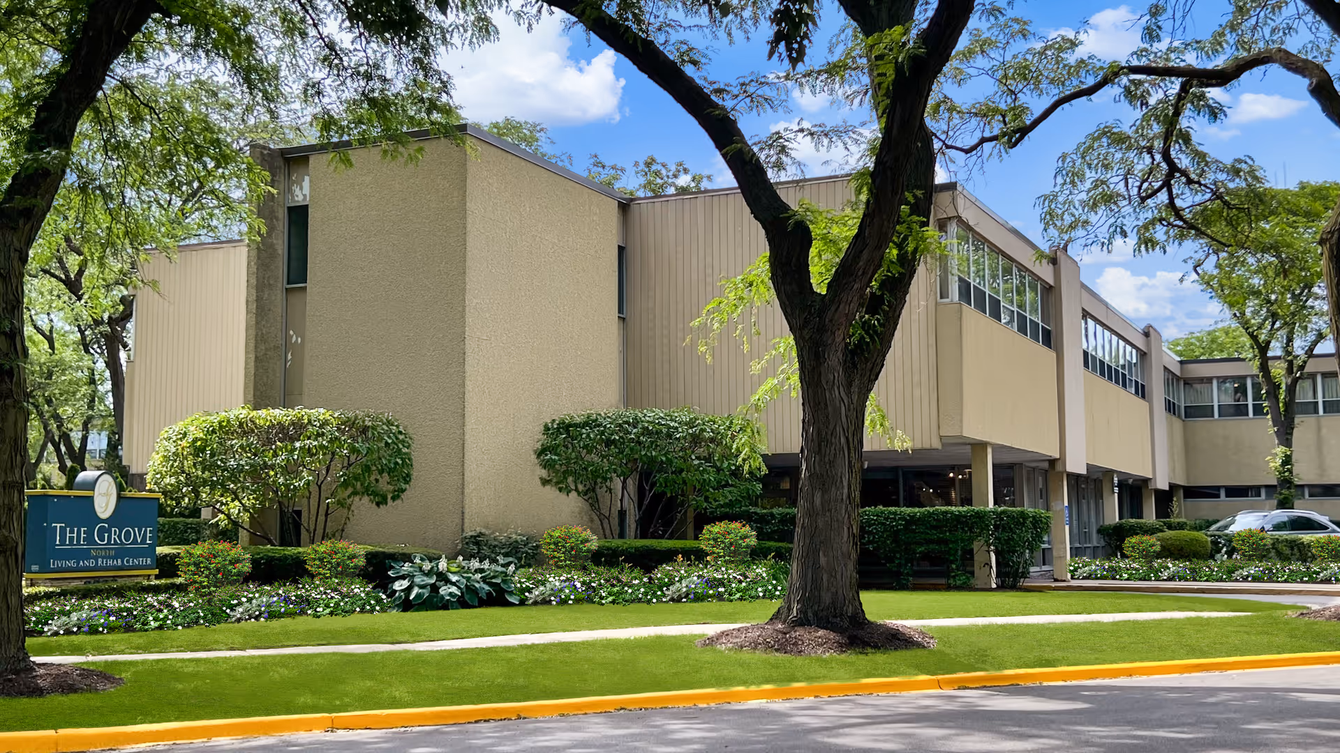 Exterior view of The Grove of Skokie senior living facility with landscaping and trees.