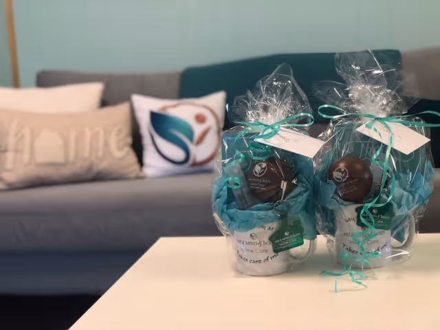 Gift baskets wrapped in clear plastic with teal ribbons sit on a white table.