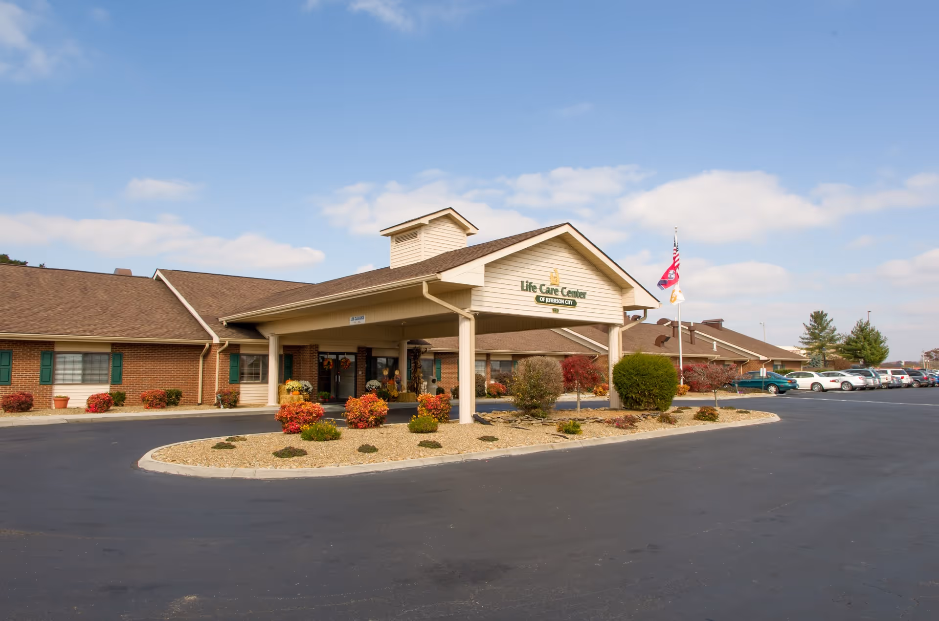 Front entrance of the Life Care Center of Jefferson City showing a covered porte-cochère, landscaped island, and parking lot.
