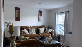 Cozy living room in a senior living facility with sofa, plants, and glass coffee table.