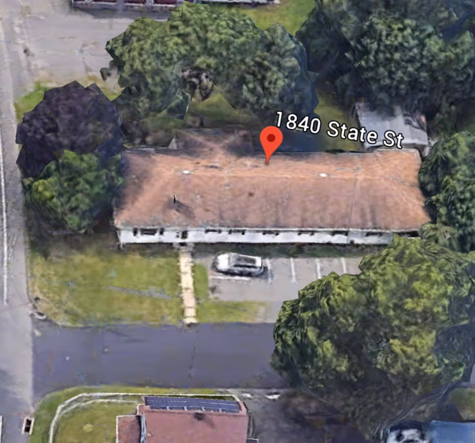 Aerial view of a single-story exterior building with a parking lot and trees.