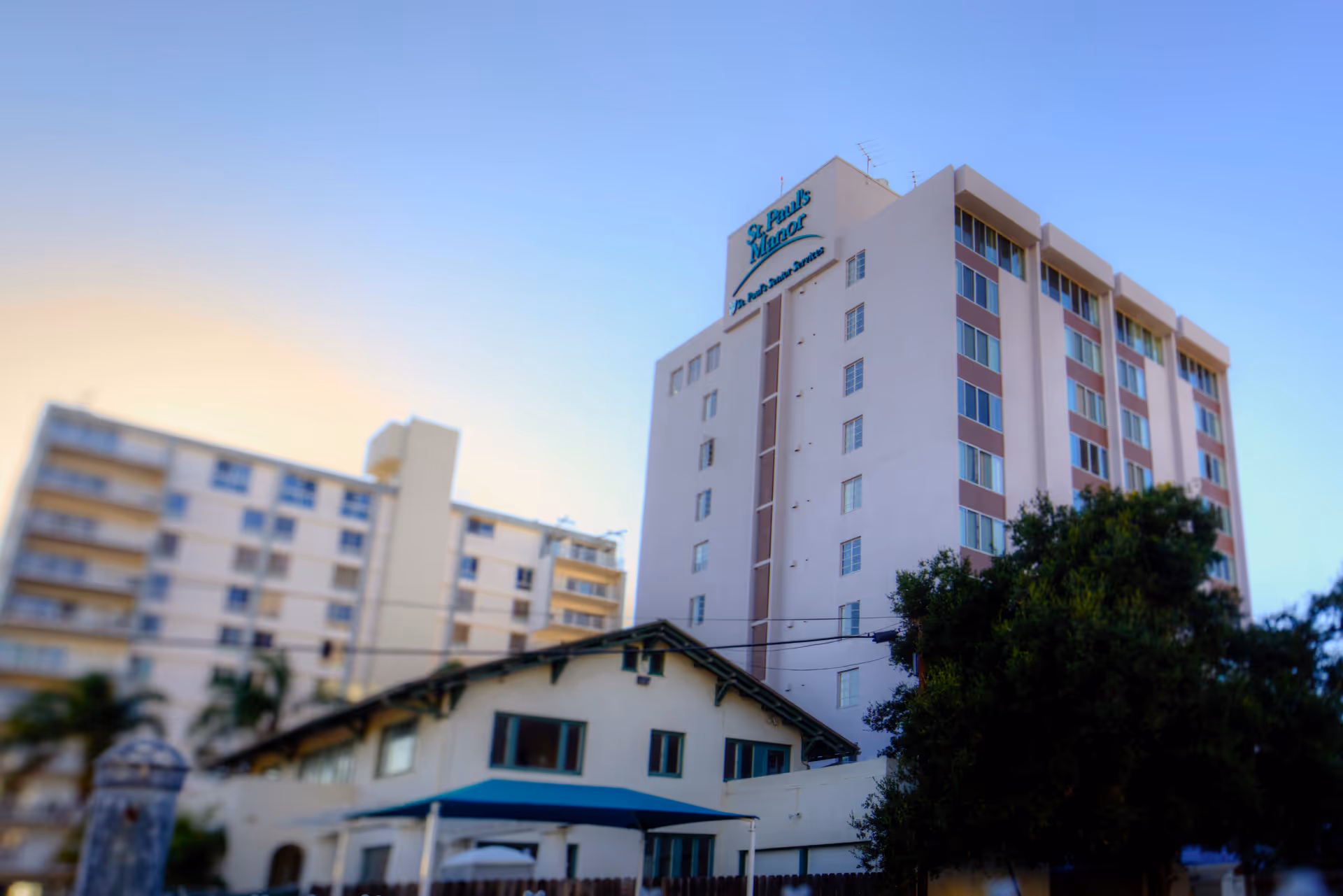 Exterior view of a tall white senior living building labeled St. Paul's Manor.