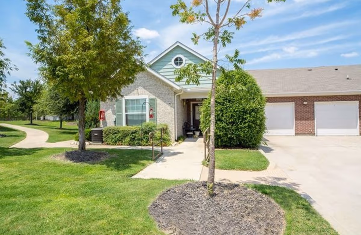 Sunstone Village exterior front with entrance, driveway, and green lawn.
