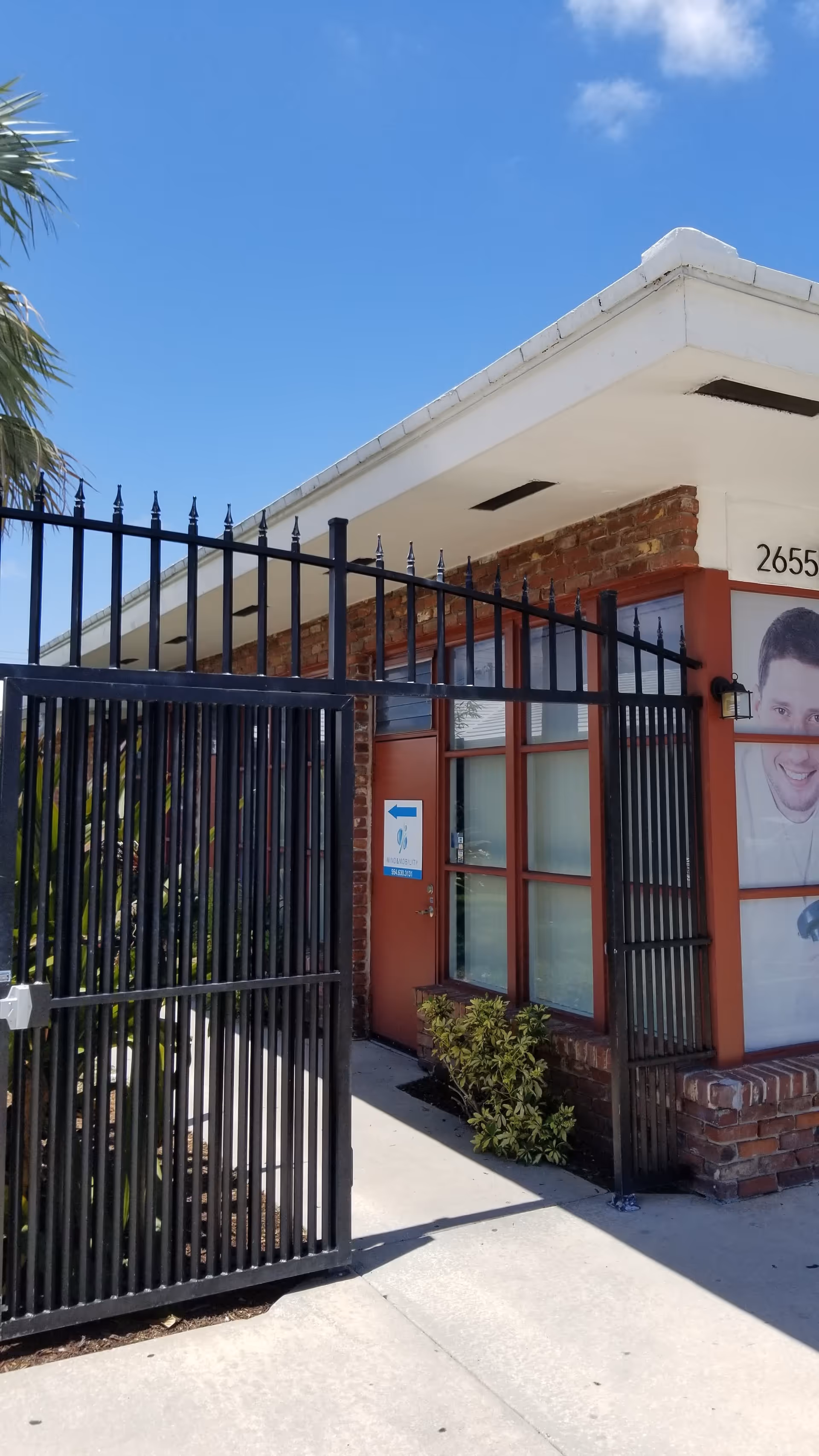 Exterior view of a Mind & Mobility facility entrance with a black gate and brick walls.