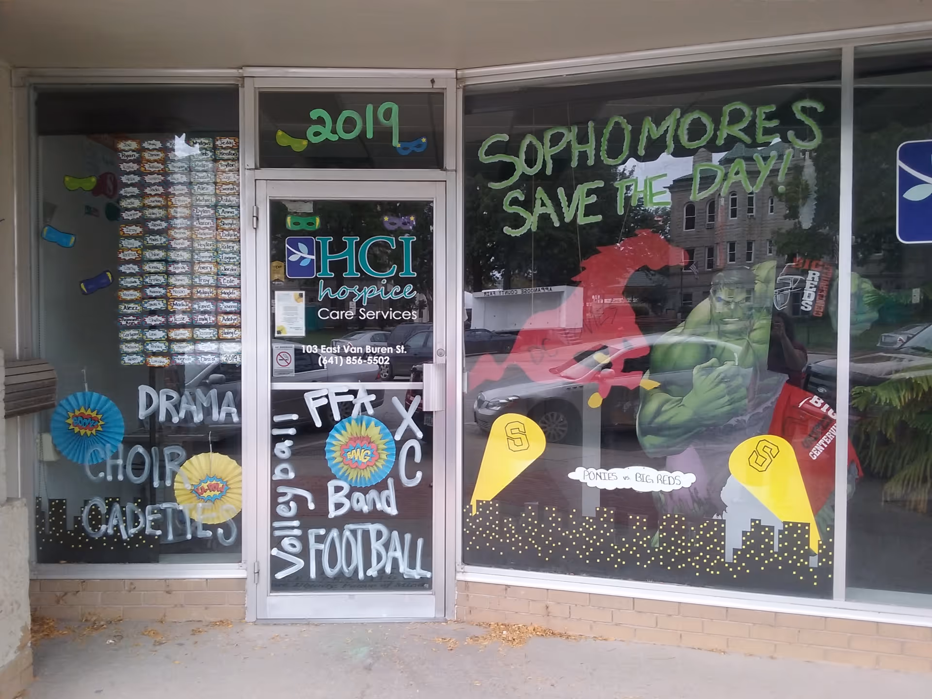 Storefront window display with colorful chalk art and hospice signage on glass doors