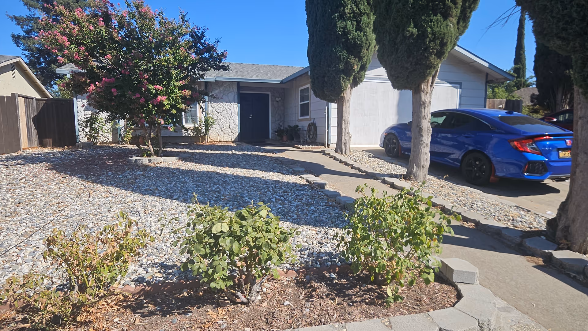 Exterior view of a single-story senior facility with a driveway and blue car.