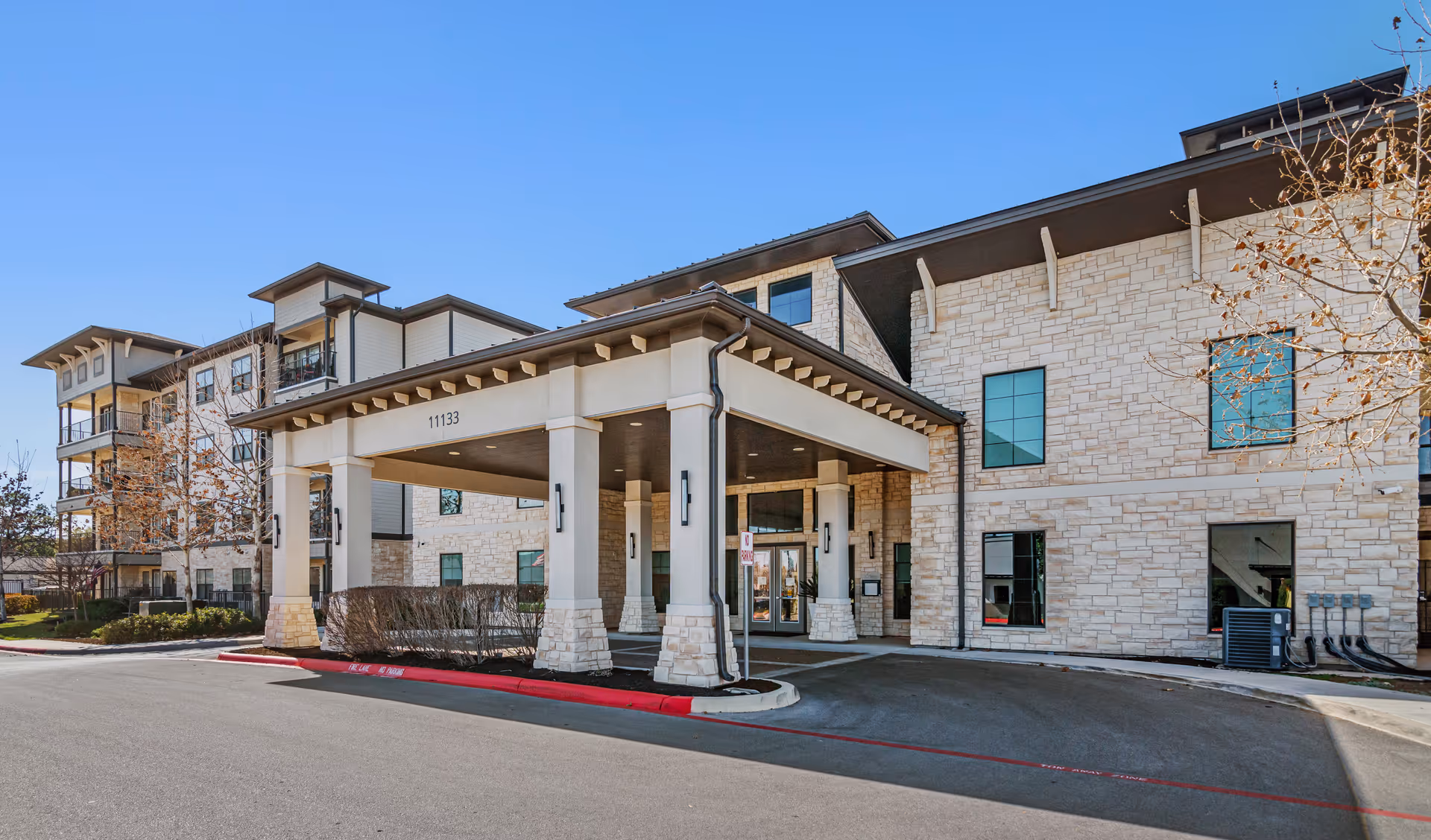 Exterior view of Solea Alamo Ranch with porte-cochere entrance and stone facade.