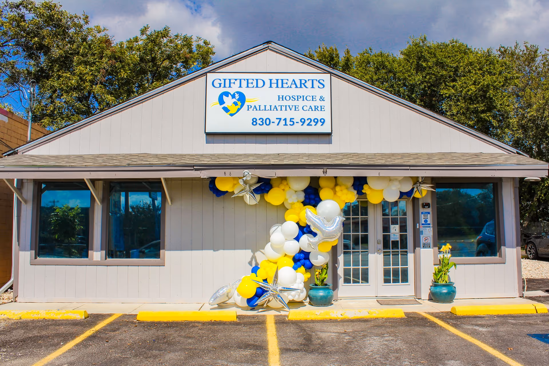 Front of Gifted Hearts Hospice & Palliative Care building decorated with balloons at entrance.