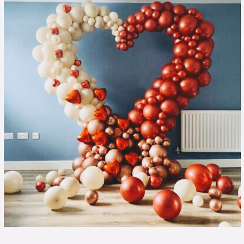 Heart-shaped balloon sculpture formed by red and white balloons in a blue-walled room.