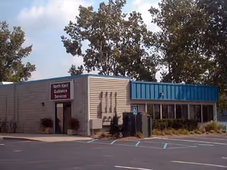 Single-story building exterior with a North Kent Guidance Services sign, parking lot in foreground.