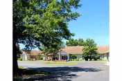 Exterior view of a single-story senior living facility entrance with trees.
