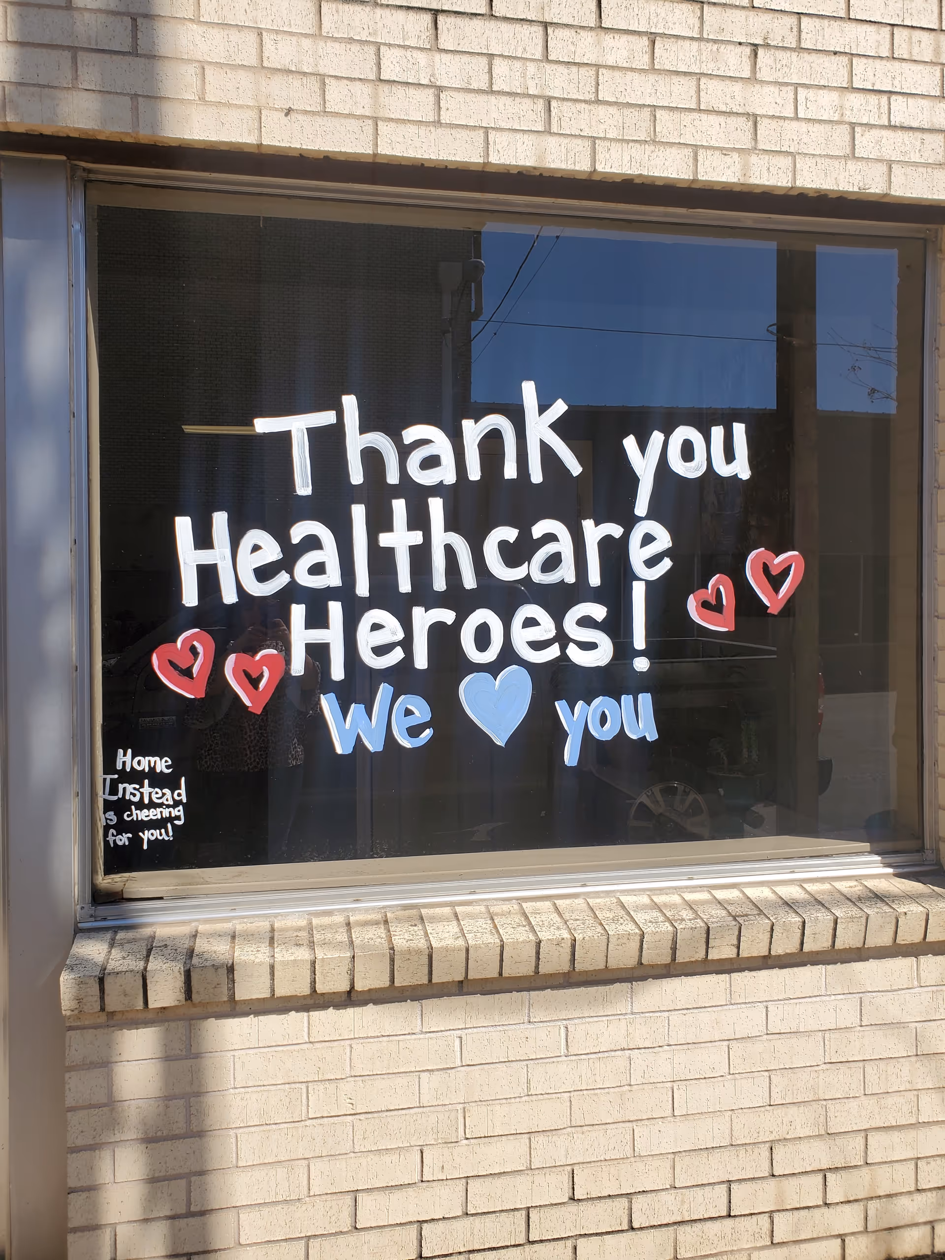 Brick building exterior with a window sign reading 'Thank you Healthcare Heroes! We love you'.