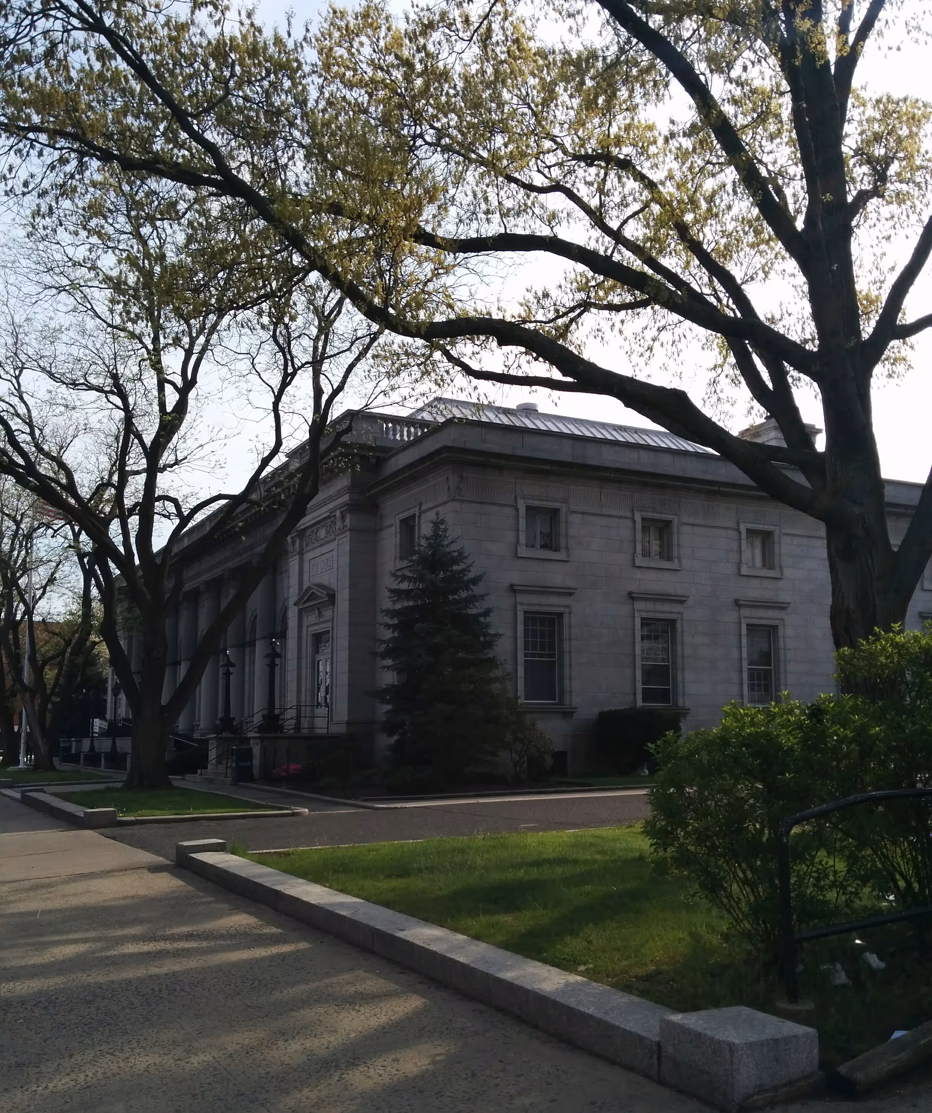 Stone building with large windows, trees, and a manicured lawn.