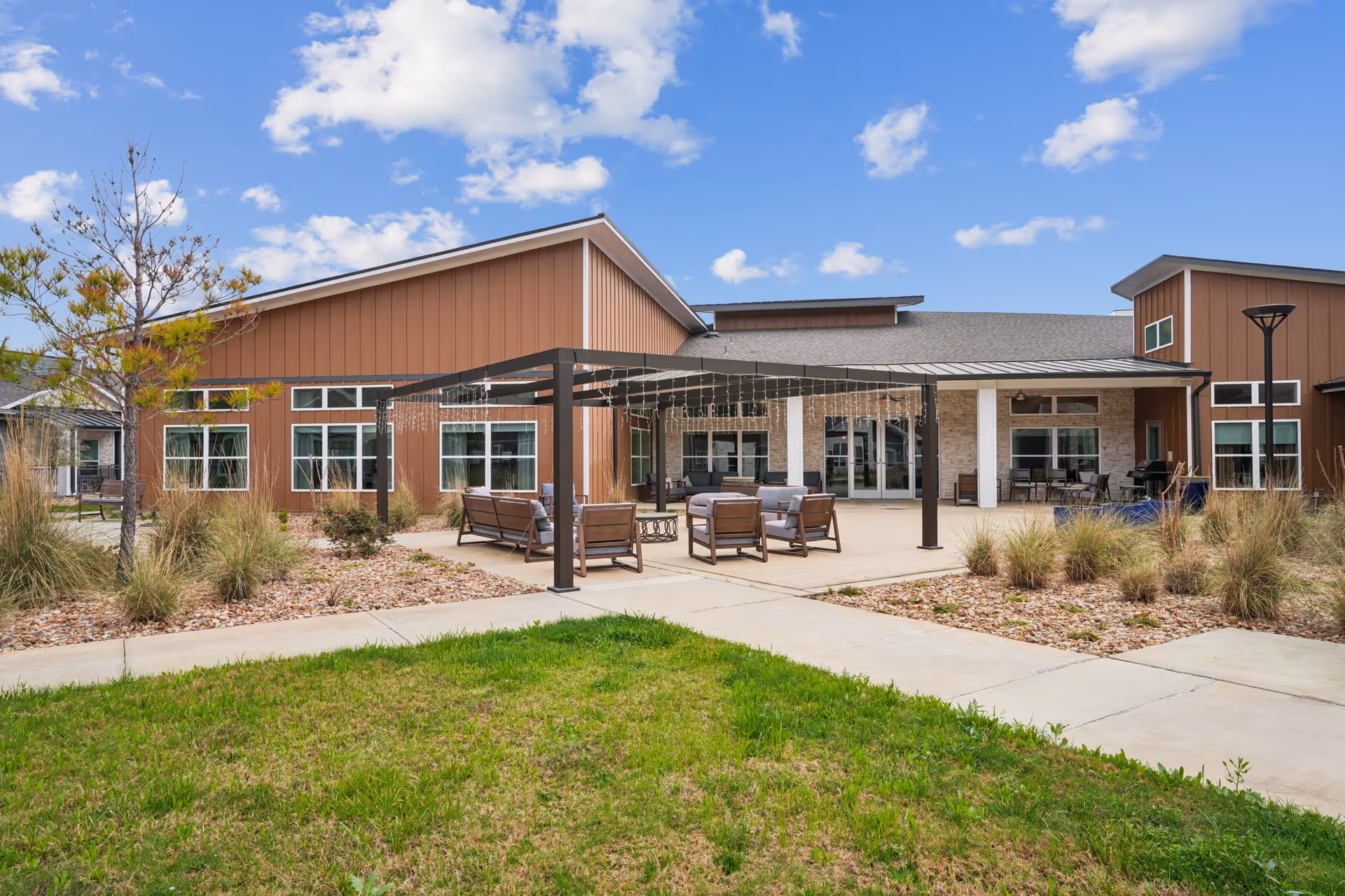 Exterior view of Landing at Woodland Lakes with a shaded patio and outdoor seating.