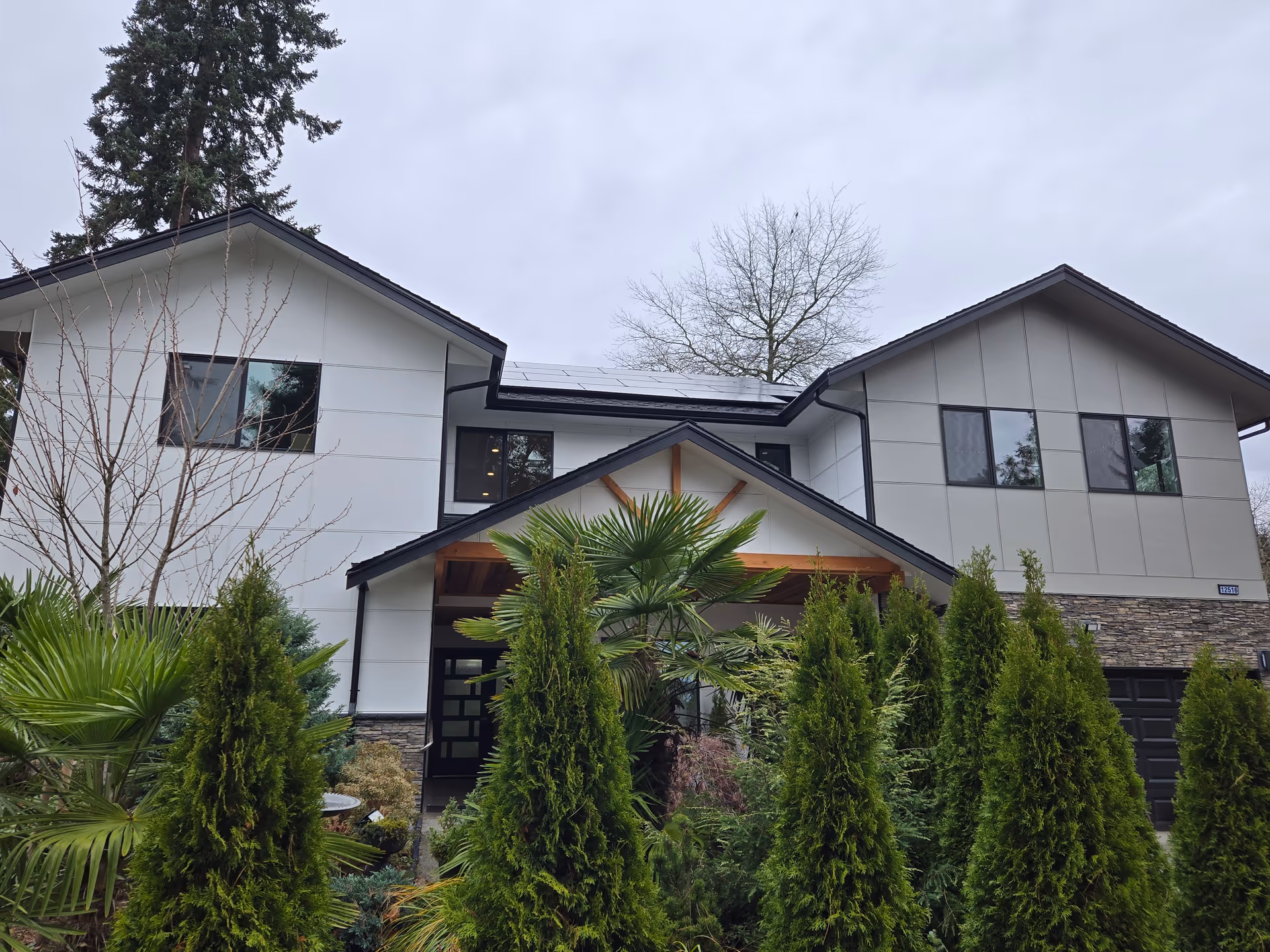 Two-story senior care facility exterior with manicured evergreens and a front entrance.