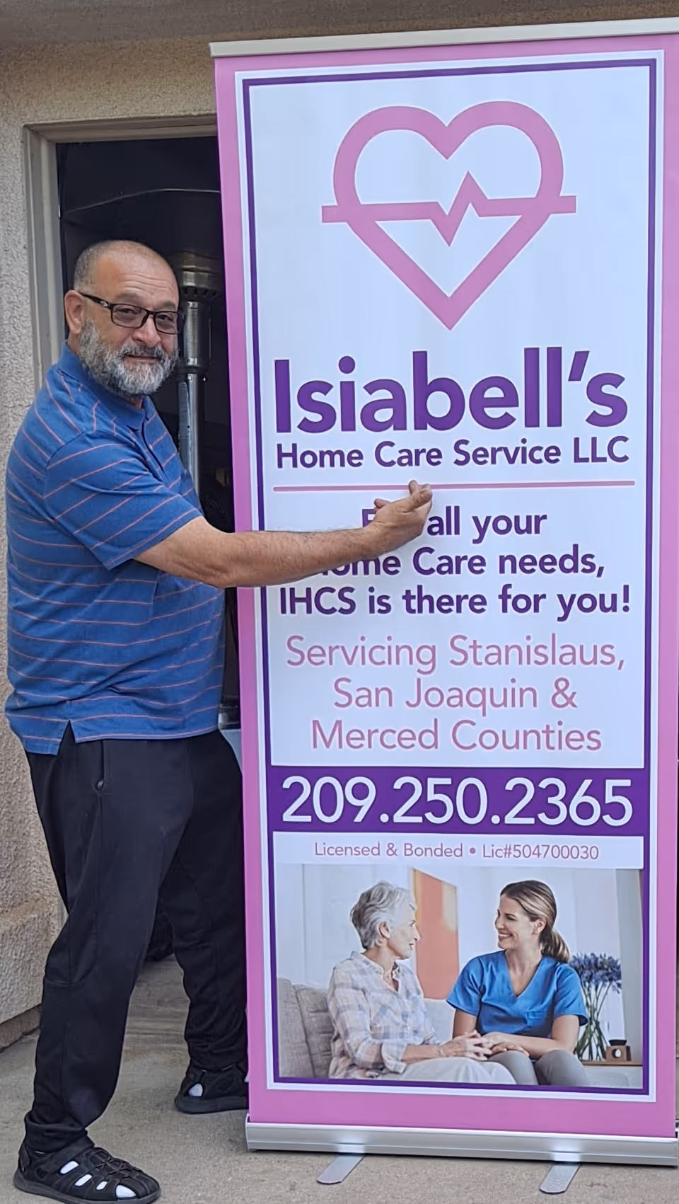 Man in blue shirt stands beside Isiabell's Home Care banner at a building entrance.