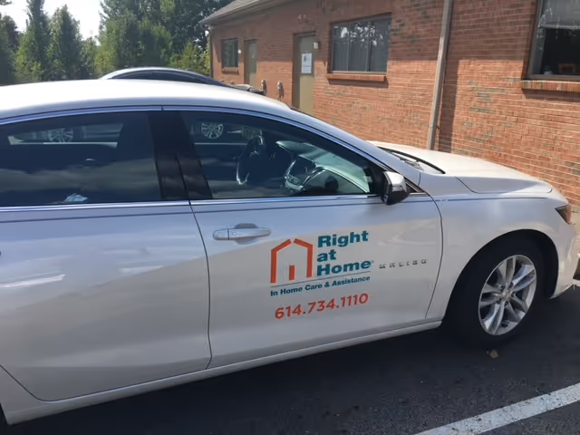 White car with Right at Home Dublin Ohio logo parked beside a brick building