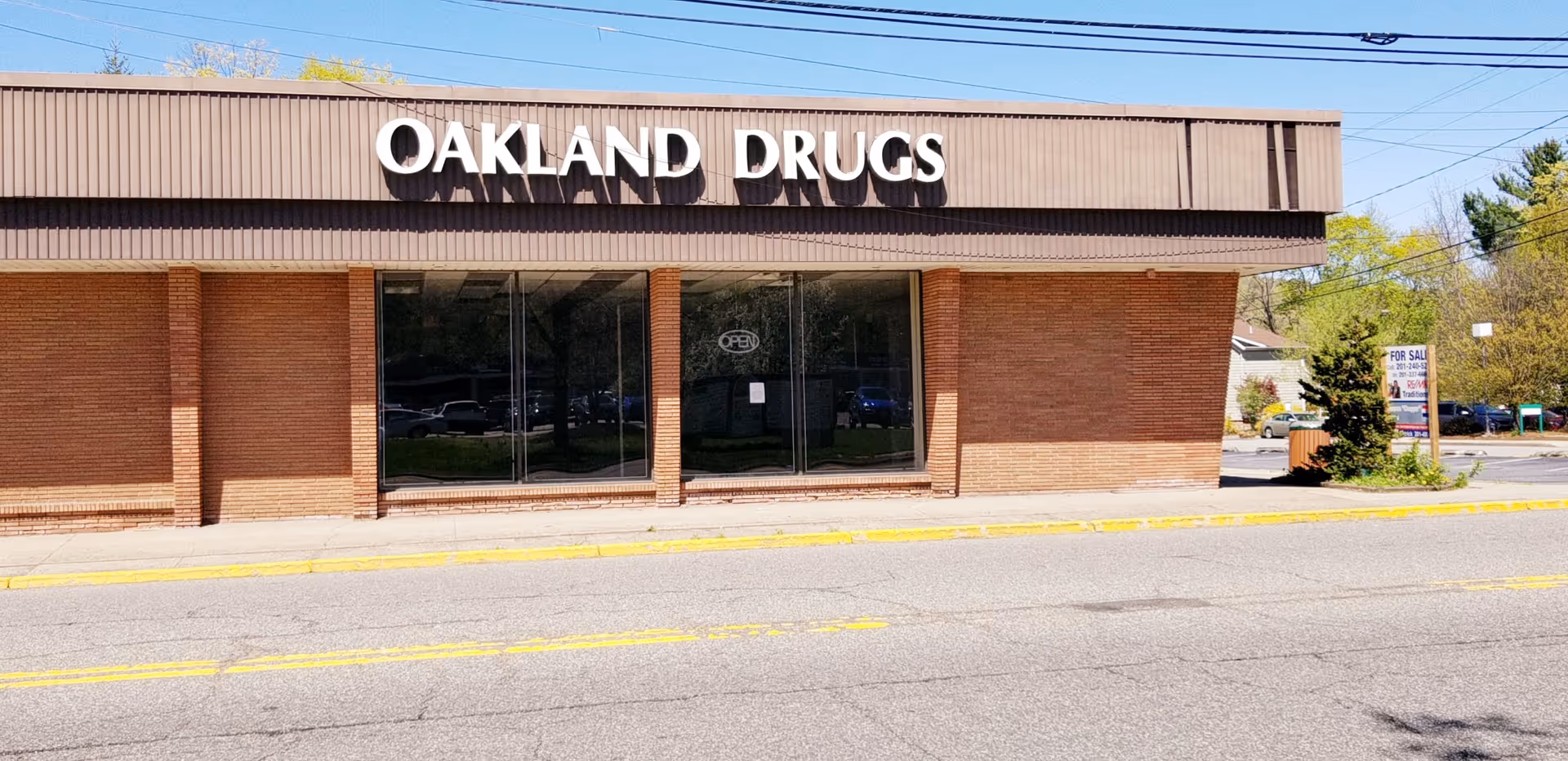 Brick storefront with Oakland Drugs sign along a busy street