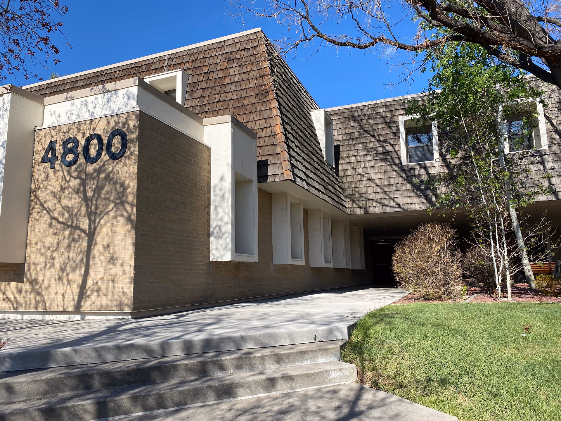 Exterior view of a beige brick senior living facility with entrance, address 4800