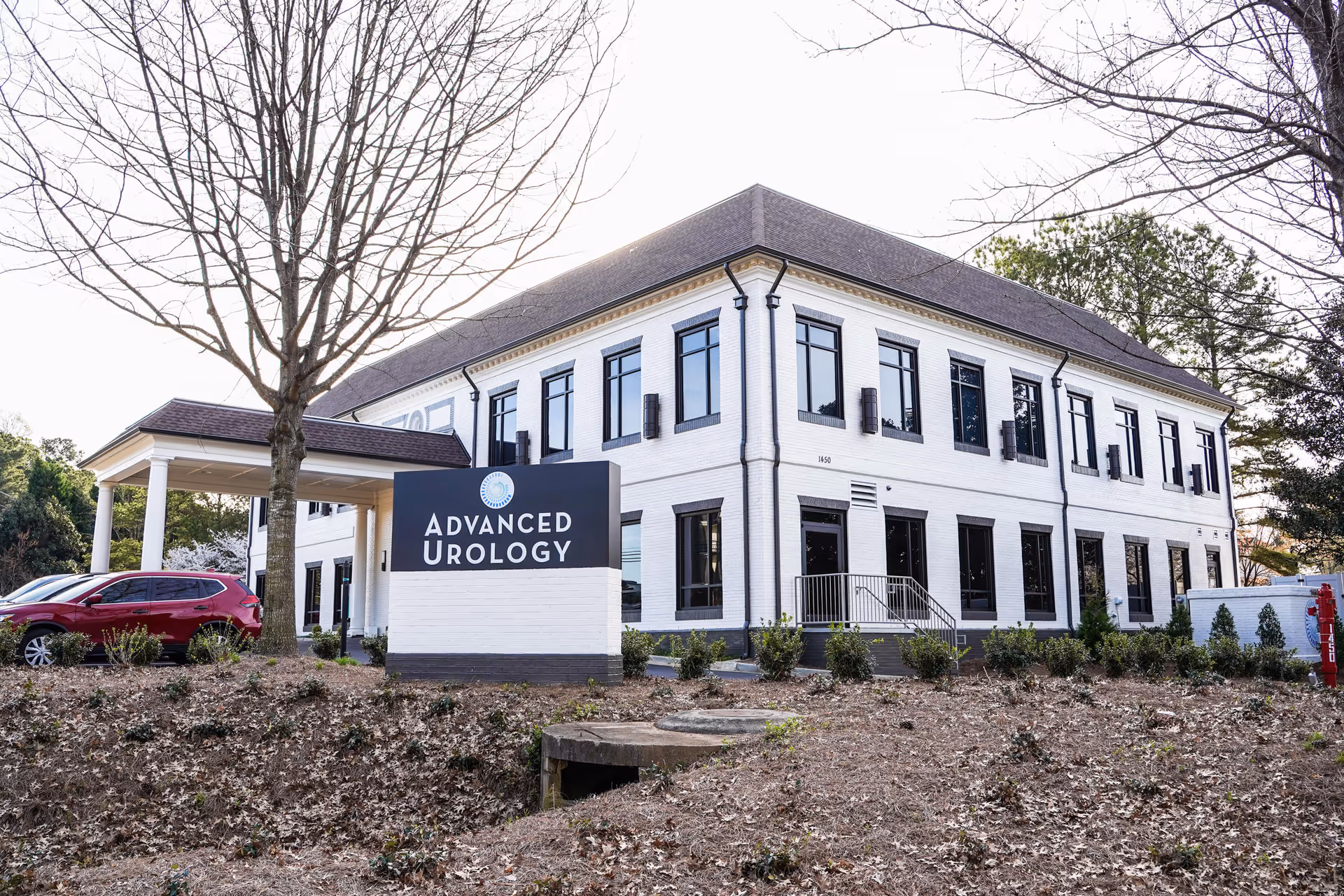 White two-story medical building with dark-framed windows and a large Advanced Urology sign.