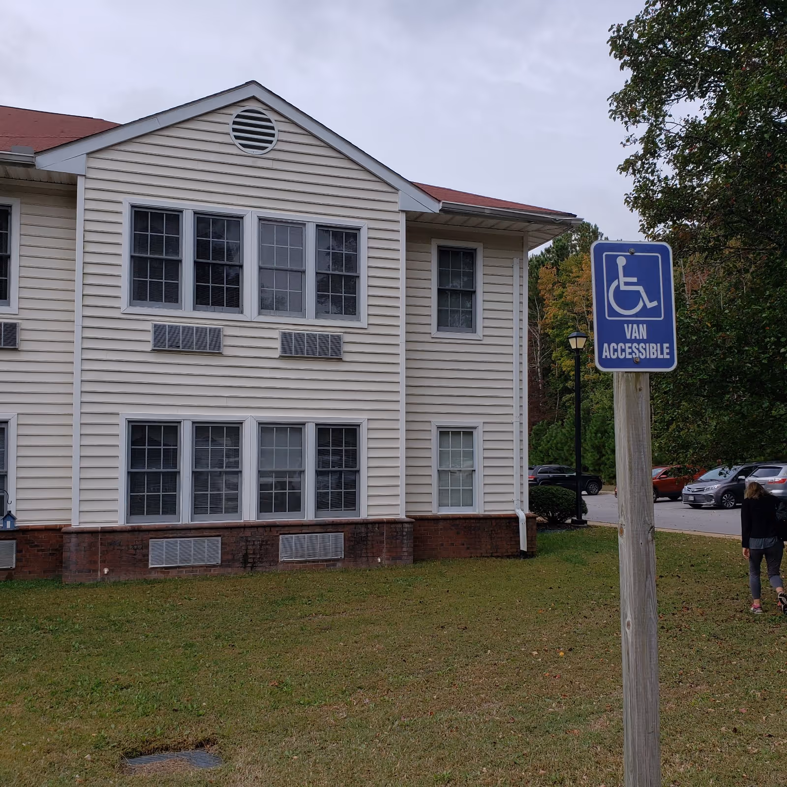 Exterior view of Hermitage at St. John's Creek building with wheelchair-accessible sign and lawn.