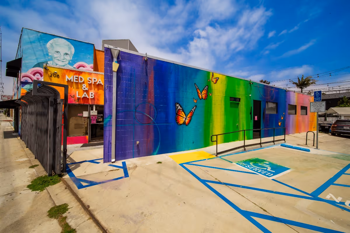 Colorful exterior wall with butterfly mural, handicap parking, and entrance to a medical facility.