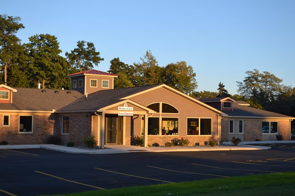 Exterior view of a single-story senior care facility with a front entrance and parking.