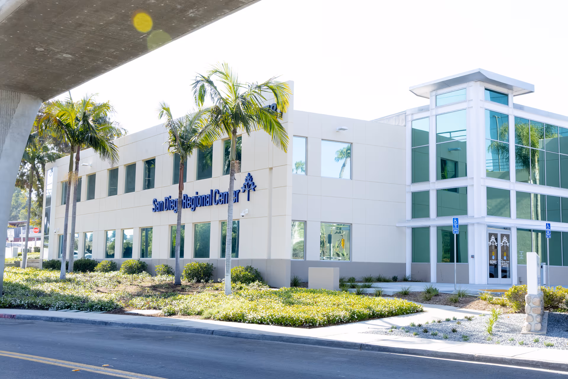 Exterior view of a modern facility building with palm trees and San Diego Regional Center signage.