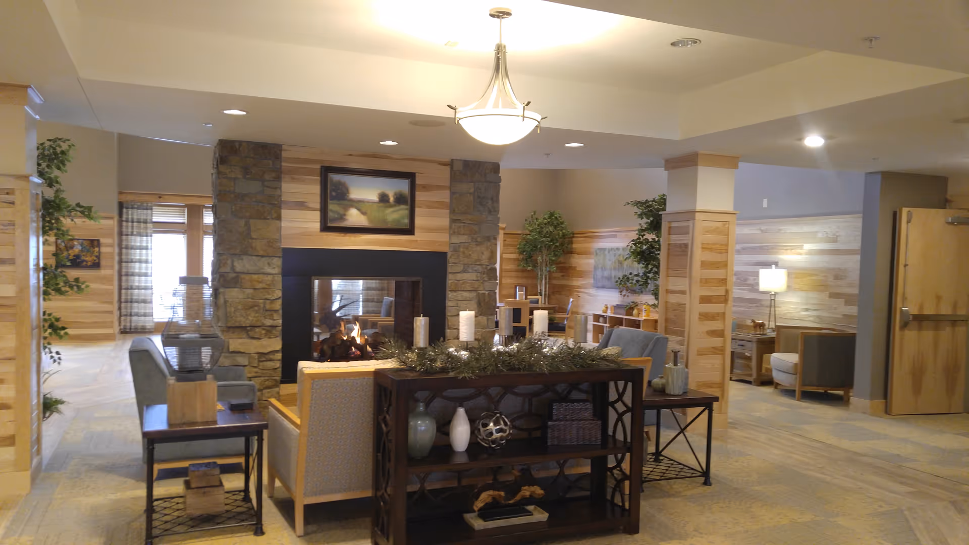 Cozy senior living lobby with fireplace, seating, and plants.
