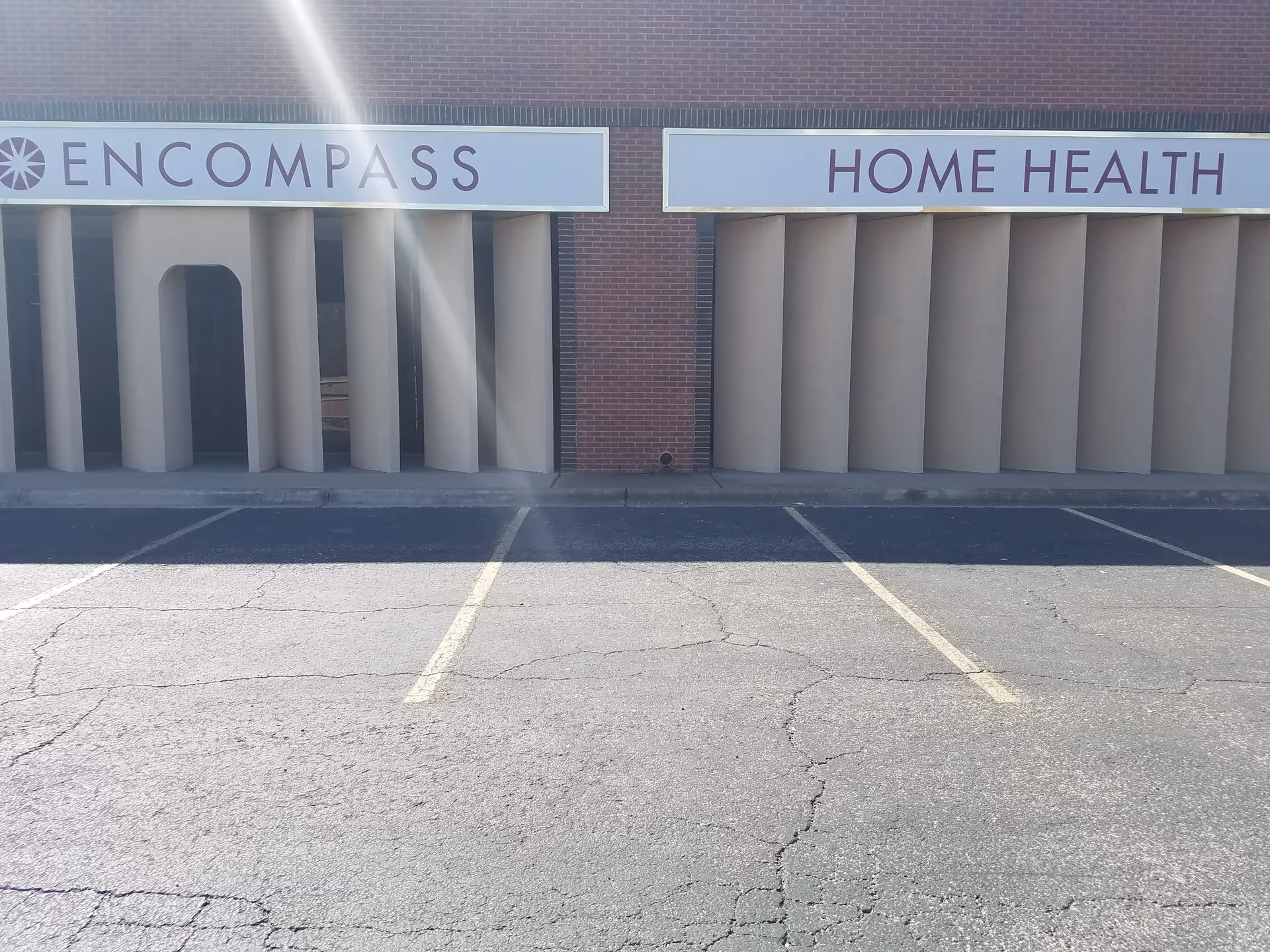Exterior view of a brick building with Encompass Home Health signs and parking.