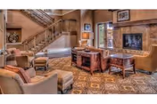 Warm, well-furnished senior living room with staircase, seating, and a stone accent wall.
