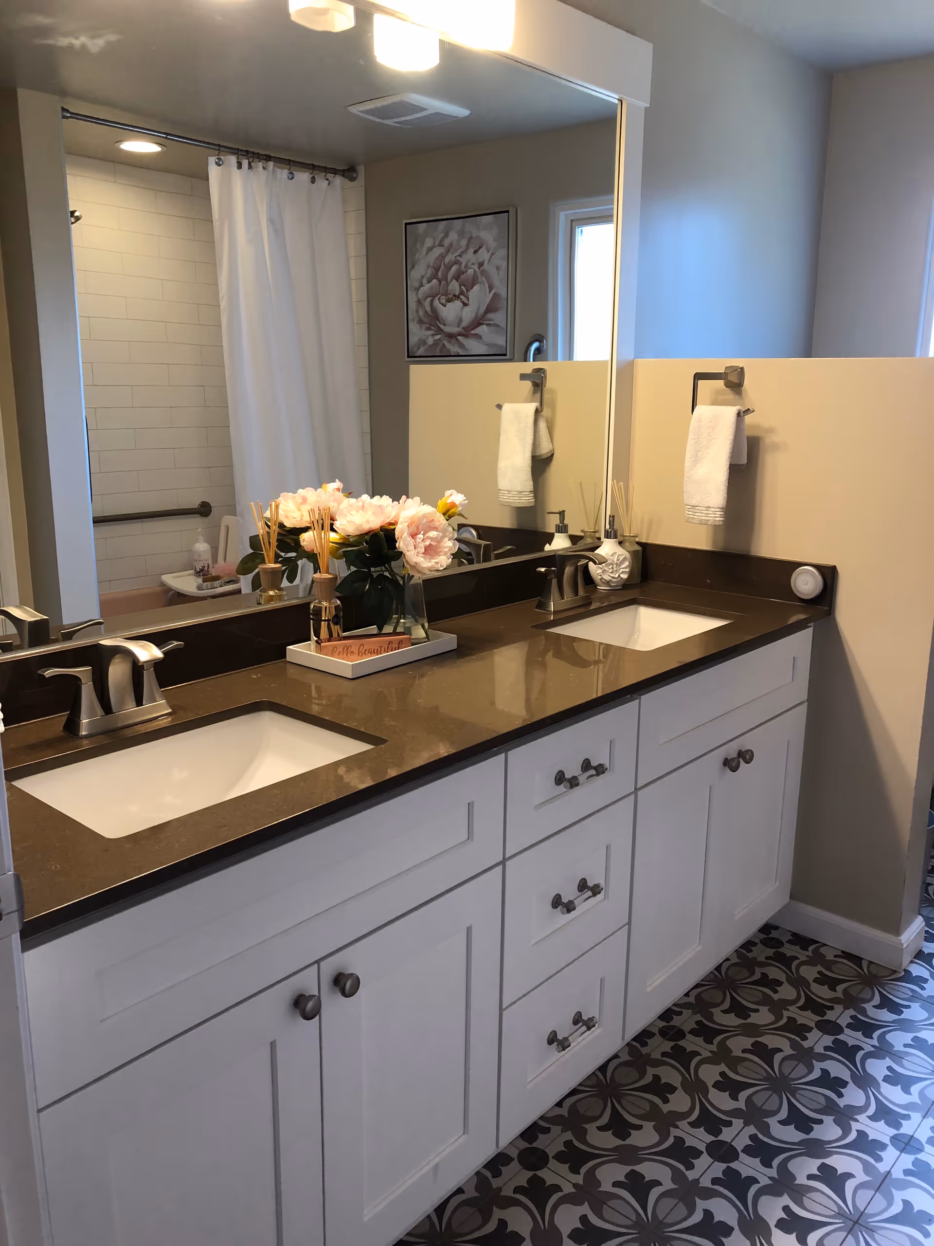 Double-sink bathroom vanity with flowers and a shower area.