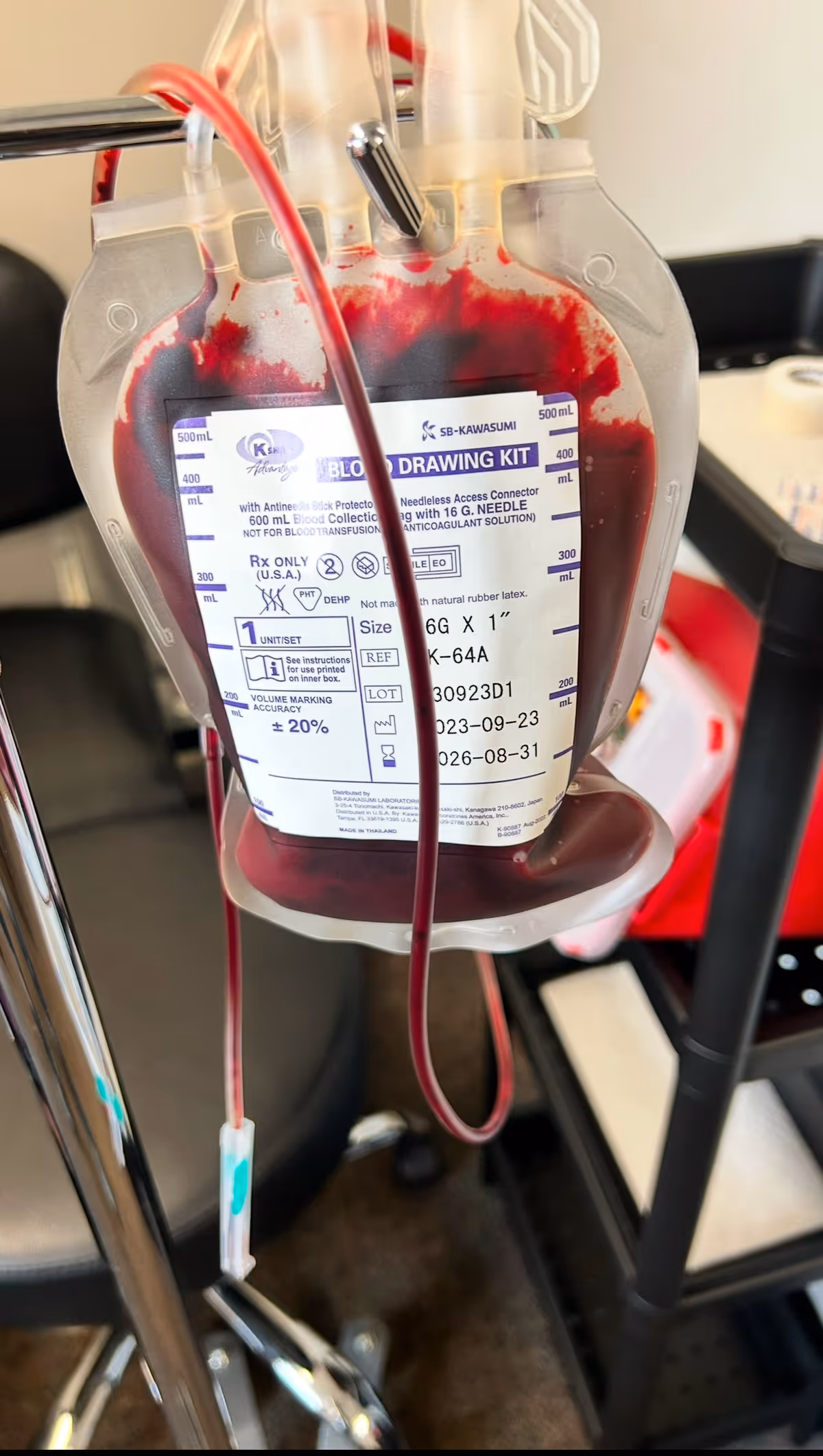 Close-up of an IV blood-drawing bag hanging from a pole in a clinical setting.