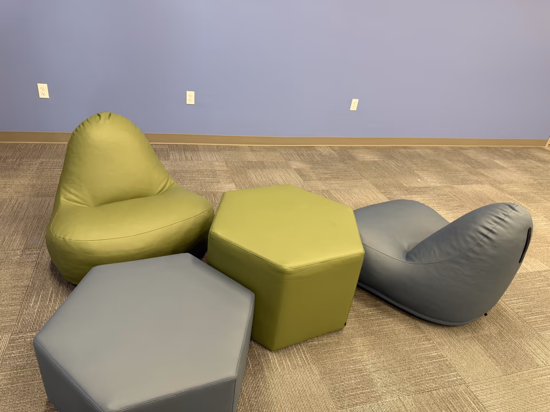 Colorful bean-bag chairs and hexagonal ottomans arranged in a lounge area.
