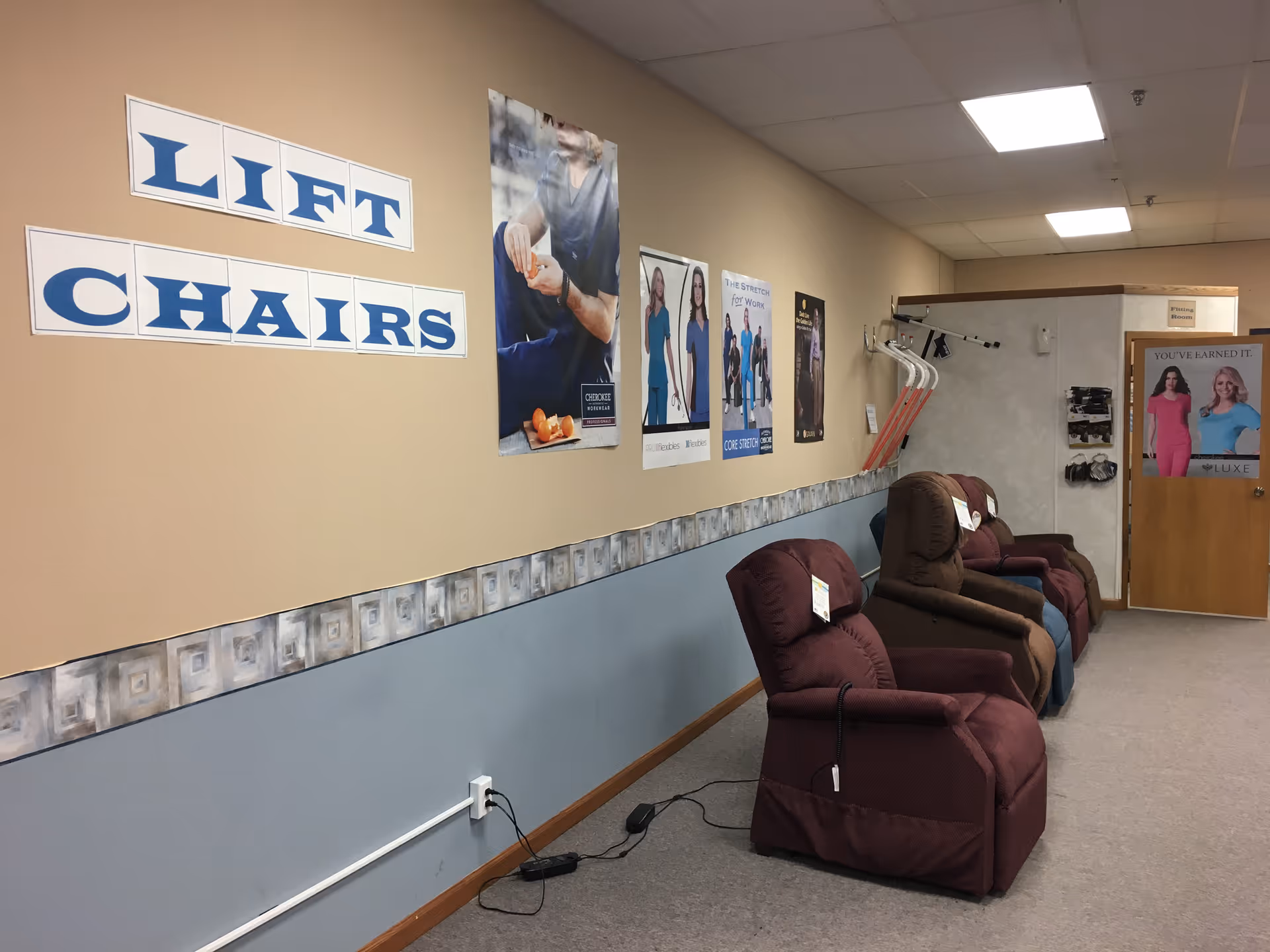 Row of maroon lift chairs along a beige wall with posters and signage.