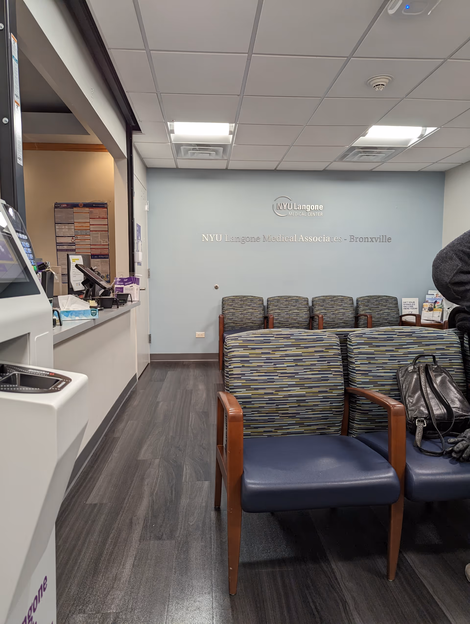 Waiting area with patterned chairs, a reception desk, and NYU Langone sign.