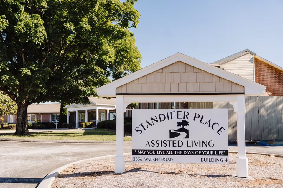 Exterior view of Standifer Place Assisted Living with a front entrance sign and trees.